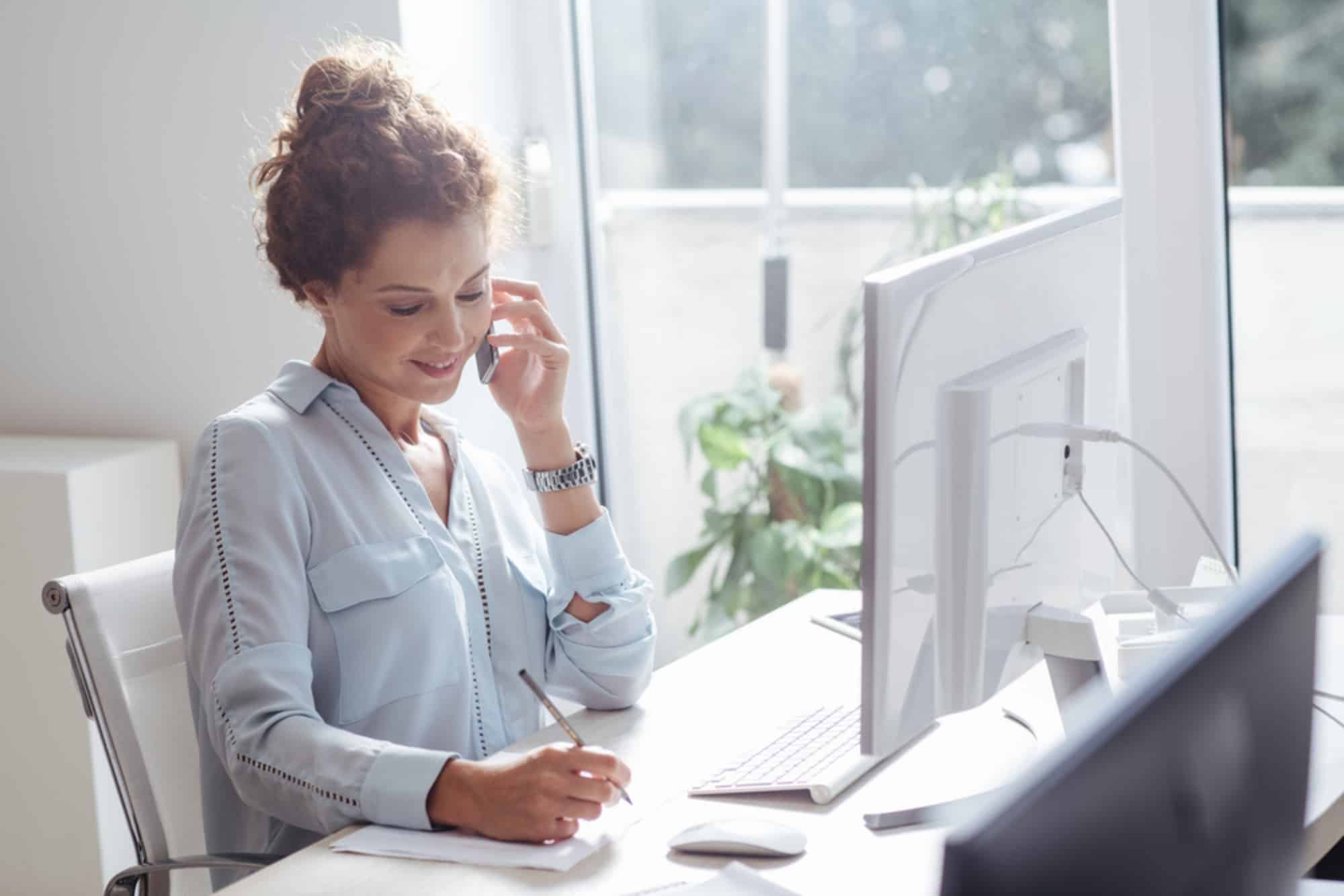 Una mujer realiza sus tareas de trabajo en comunicación con otros compañeros.